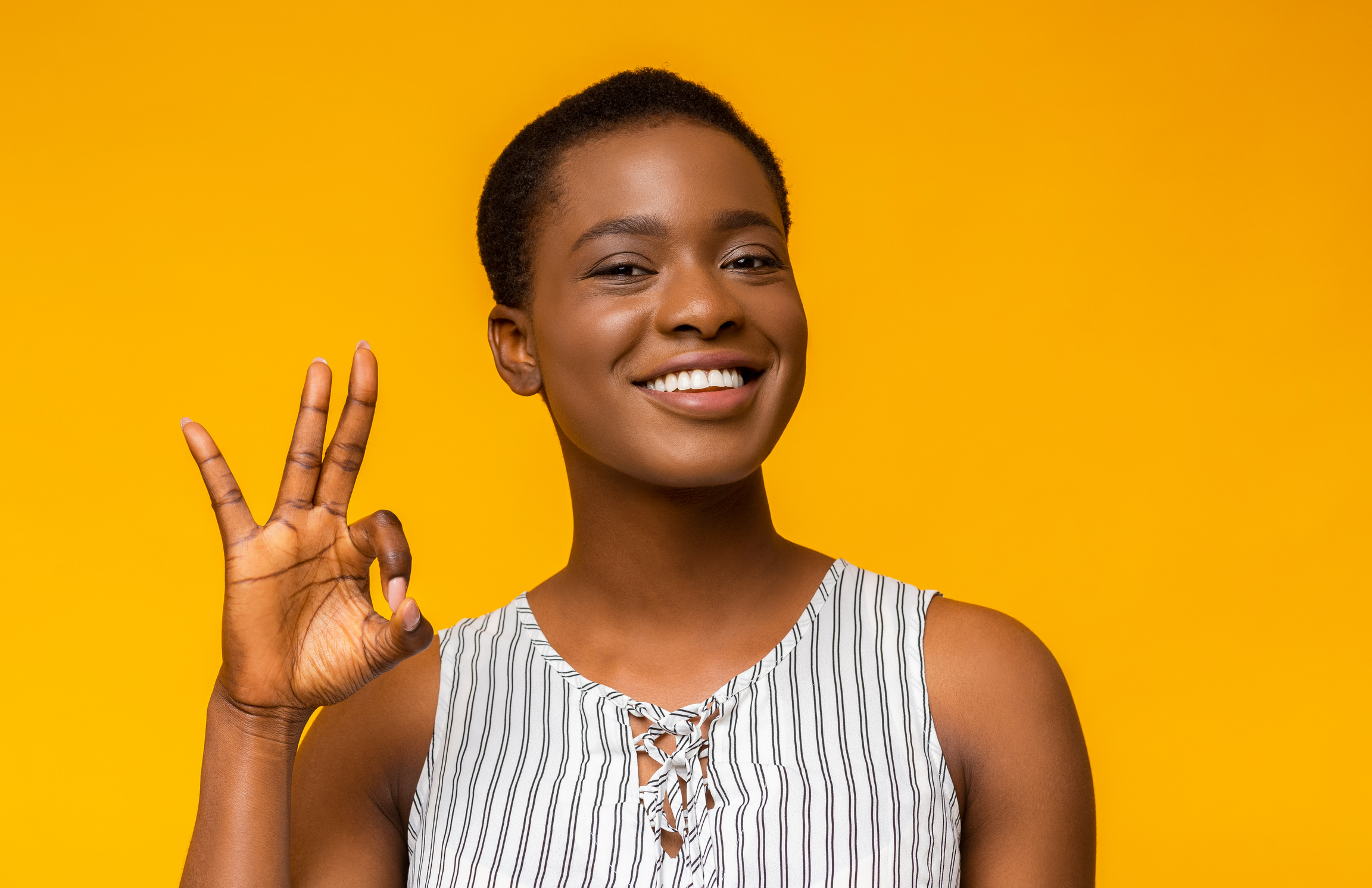 Happy black woman gesturing OK sign and smiling